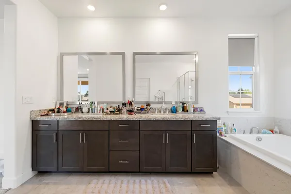 a bathroom with a tub double vanity sink and mirror