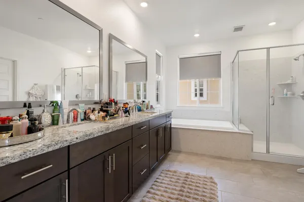 a bathroom with a granite countertop double vanity sink a mirror and a bathtub