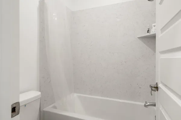 a white bath tub sitting next to a white toilet and vanity