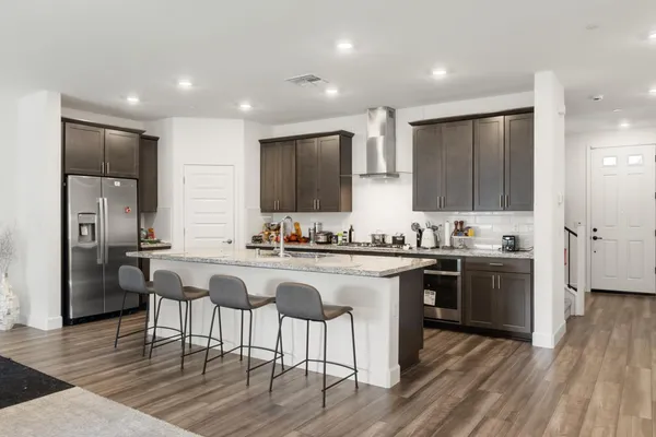 a kitchen with stainless steel appliances granite countertop a kitchen island hardwood floor sink stove dining table and chairs