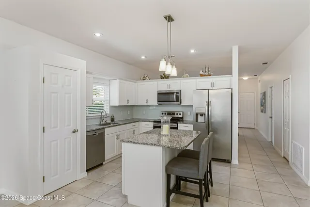 a kitchen with stainless steel appliances kitchen island granite countertop a sink a stove a refrigerator and island