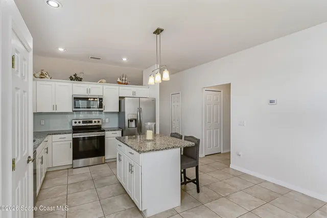 a kitchen with stainless steel appliances kitchen island granite countertop a refrigerator a stove a oven and a sink with granite countertops