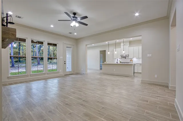 a view of an empty room with wooden floor and a ceiling fan