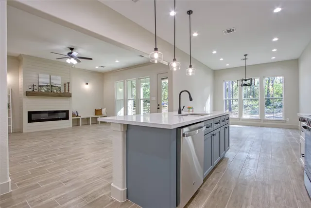 a large kitchen with granite countertop a large counter top a sink stainless steel appliances and cabinets