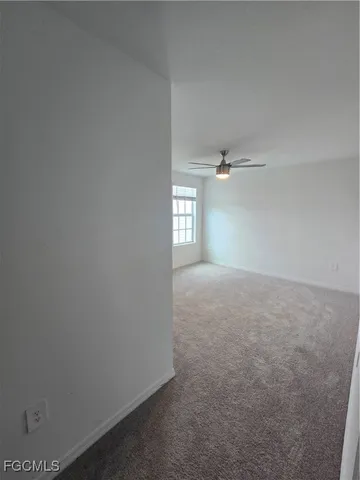 an empty room with windows and ceiling fan