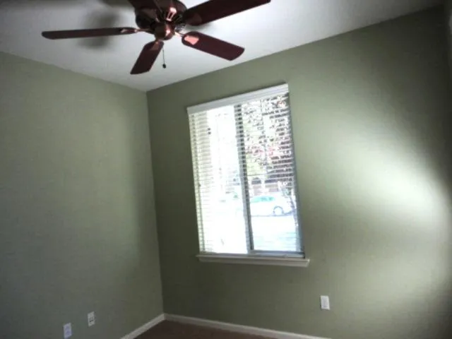 an empty room with a window and a fan