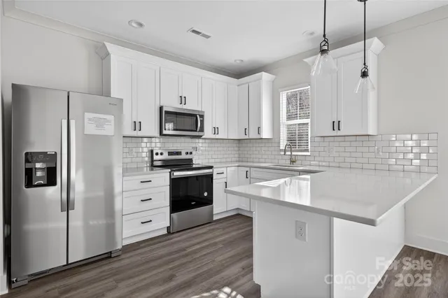 a kitchen with stainless steel appliances a stove a refrigerator and white cabinets