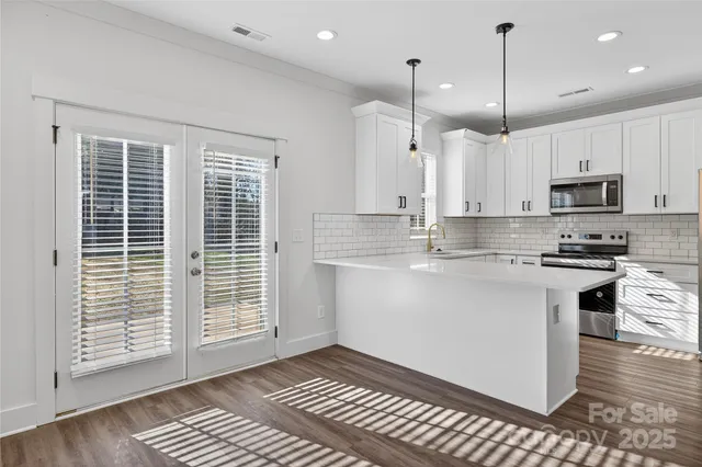 a kitchen with stainless steel appliances a stove a refrigerator a sink and white cabinets