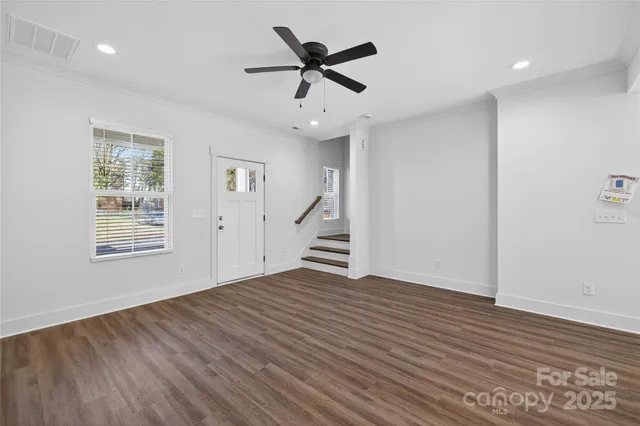 a view of an empty room with a window and wooden floor