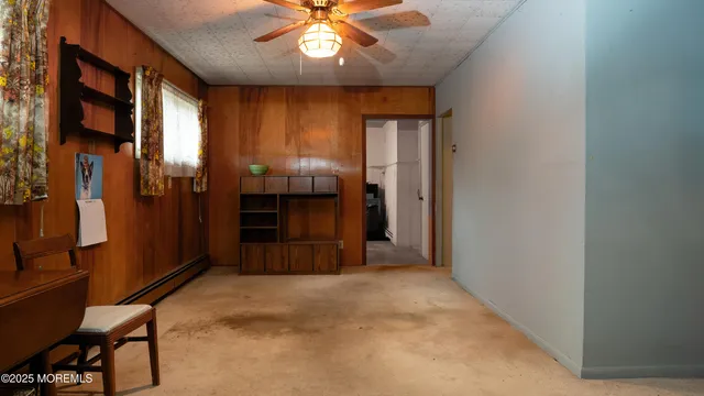 an empty room with chandelier fan and windows