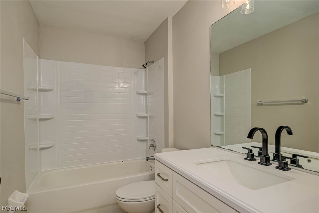 704 Ichabod Avenue Lehigh Acres, FL 33973 - Photo 14 of 22 a bathroom with a granite countertop sink toilet and shower