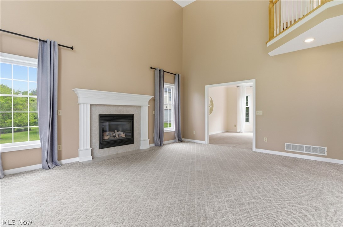 11678 Dunham Road Northfield, OH 44067 - Photo 9 of 38 Spacious living area featuring a decorative fireplace with a white mantel, high ceilings, large windows, light patterned carpeting, and an arched entryway