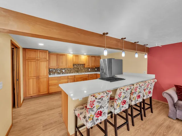 a kitchen with stainless steel appliances kitchen island granite countertop a table chairs and a refrigerator