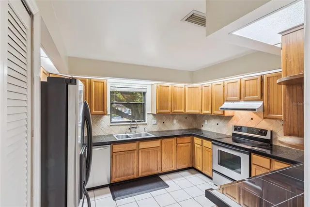 a kitchen with a sink cabinets stainless steel appliances and a window