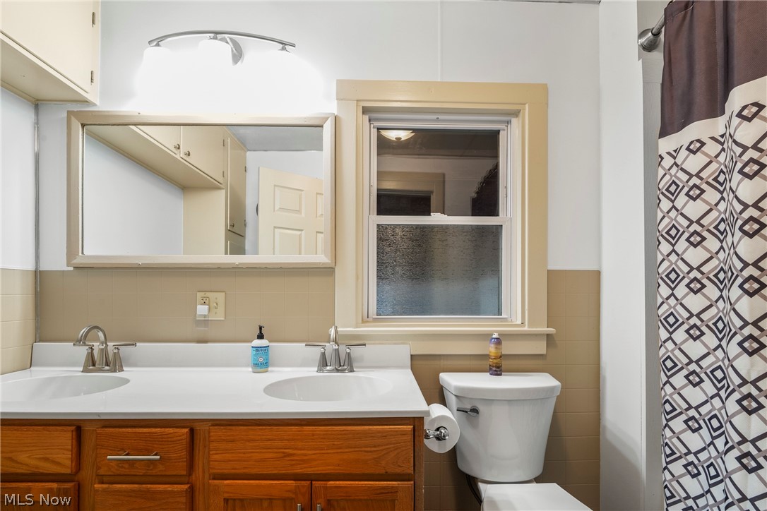 629 Clinton Street Niles, OH 44446 - Photo 18 of 50 Dual vanity with white countertop and integrated sinks, wood-finish cabinetry, framed mirror, and overhead light fixture