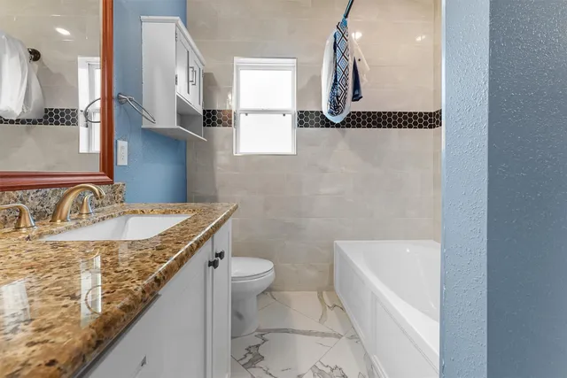 a bathroom with a granite countertop sink a toilet and bathtub