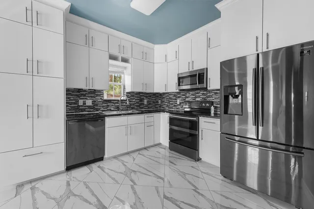 a kitchen with stainless steel appliances a refrigerator sink and microwave