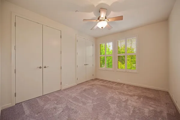 an empty room with windows and fan