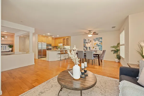 a living room with furniture kitchen view and a chandelier