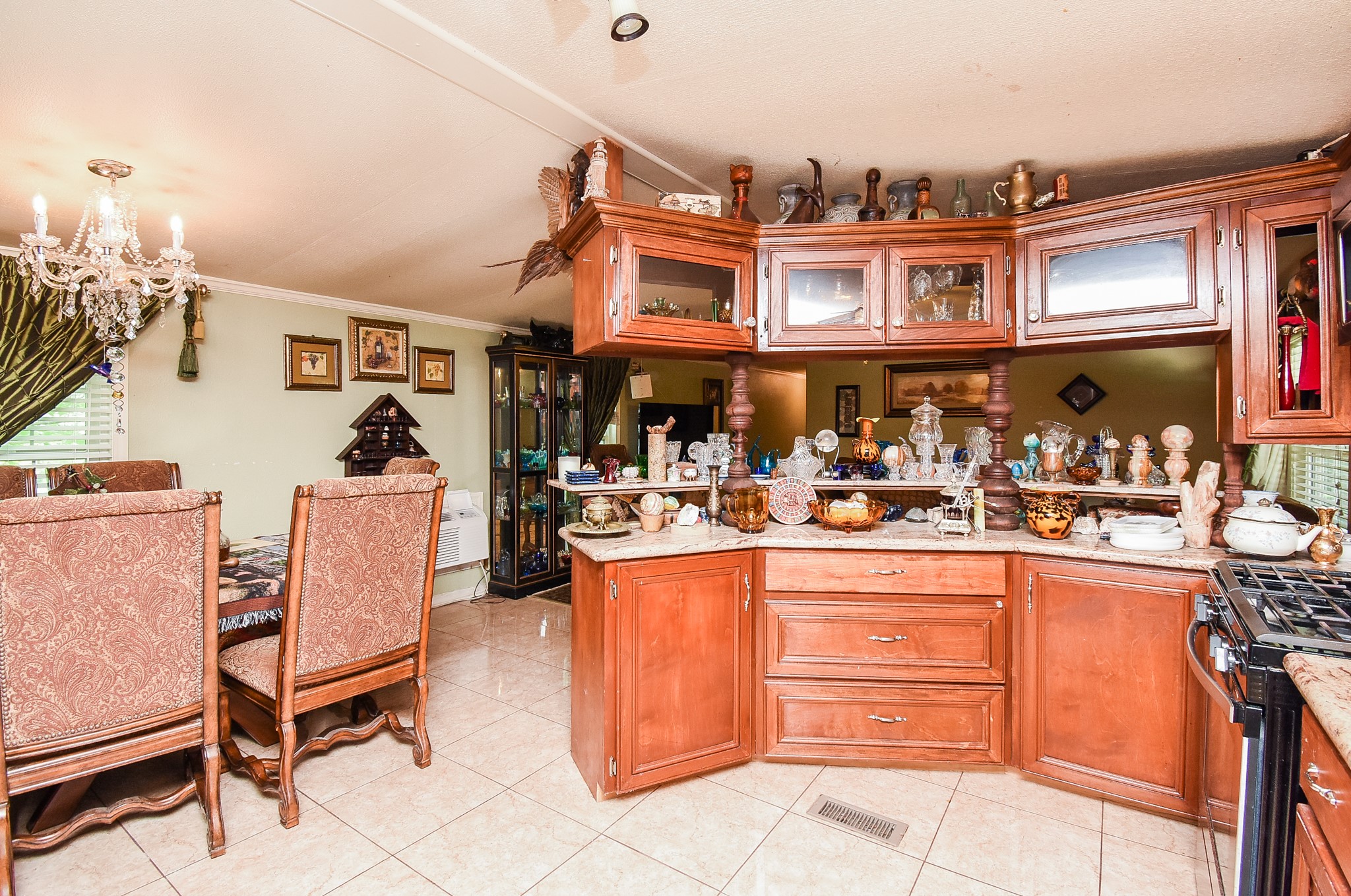 39551 Donigan Road Brookshire, TX 77423 - Photo 20 of 37 Kitchen with wood finish cabinetry, glass insert cabinets, a peninsula, ornamental molding, and light tile patterned floors