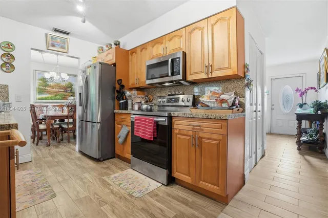 a kitchen with stainless steel appliances granite countertop a refrigerator and a stove top oven