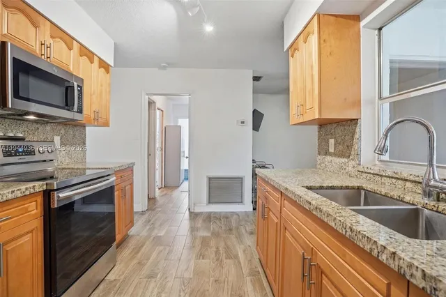 a kitchen with stainless steel appliances granite countertop a sink and a stove