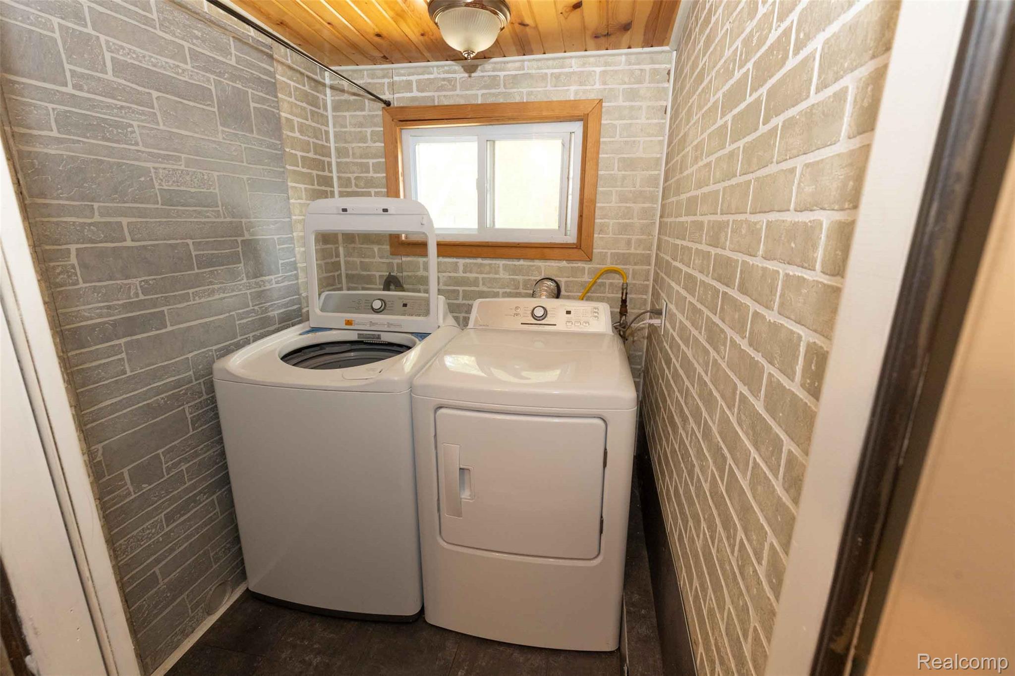 5761 Genesee Road Lapeer, MI 48446 - Photo 22 of 52 Dedicated utility space featuring textured wall finishes, a wood-paneled ceiling, and a bright window with wood trim