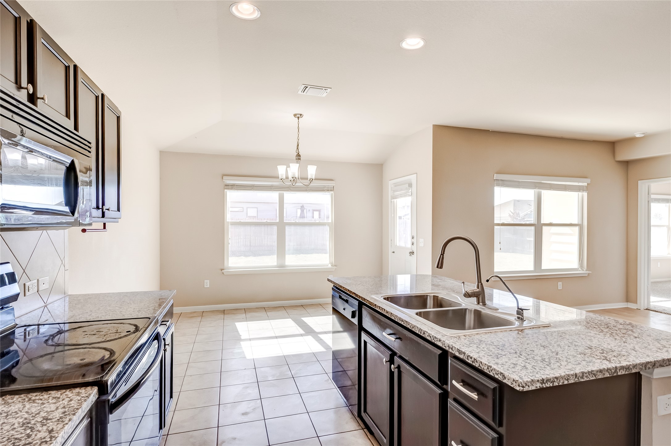 100 Sulphur River Loop Hutto, TX 78634 - Photo 10 of 16 Kitchen featuring black appliances, dark brown cabinetry, pendant lighting, light tile patterned floors, and recessed lighting