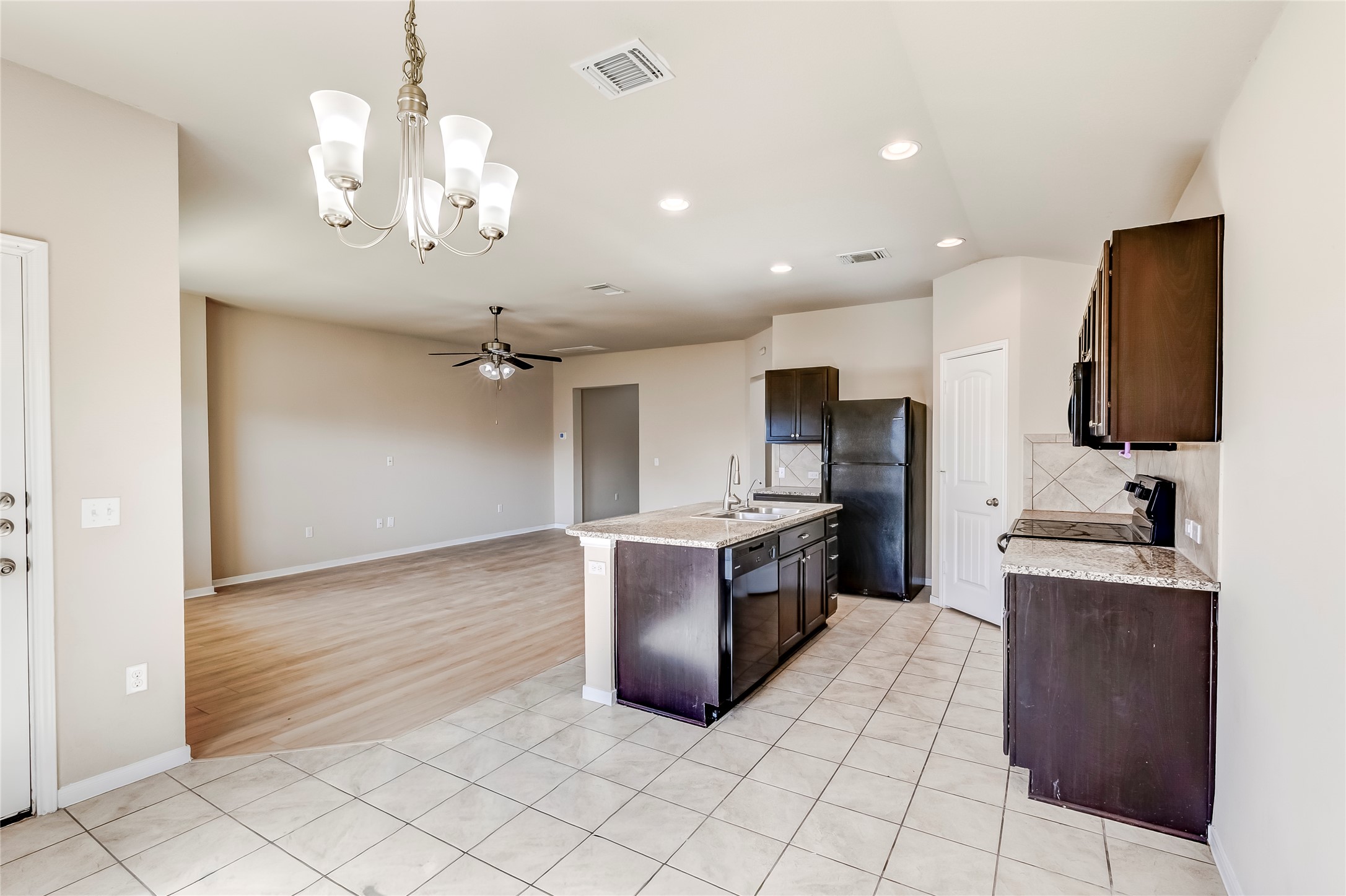 100 Sulphur River Loop Hutto, TX 78634 - Photo 16 of 16 Kitchen with light tile patterned floors, dark brown cabinets, pendant lighting, black appliances, and open floor plan