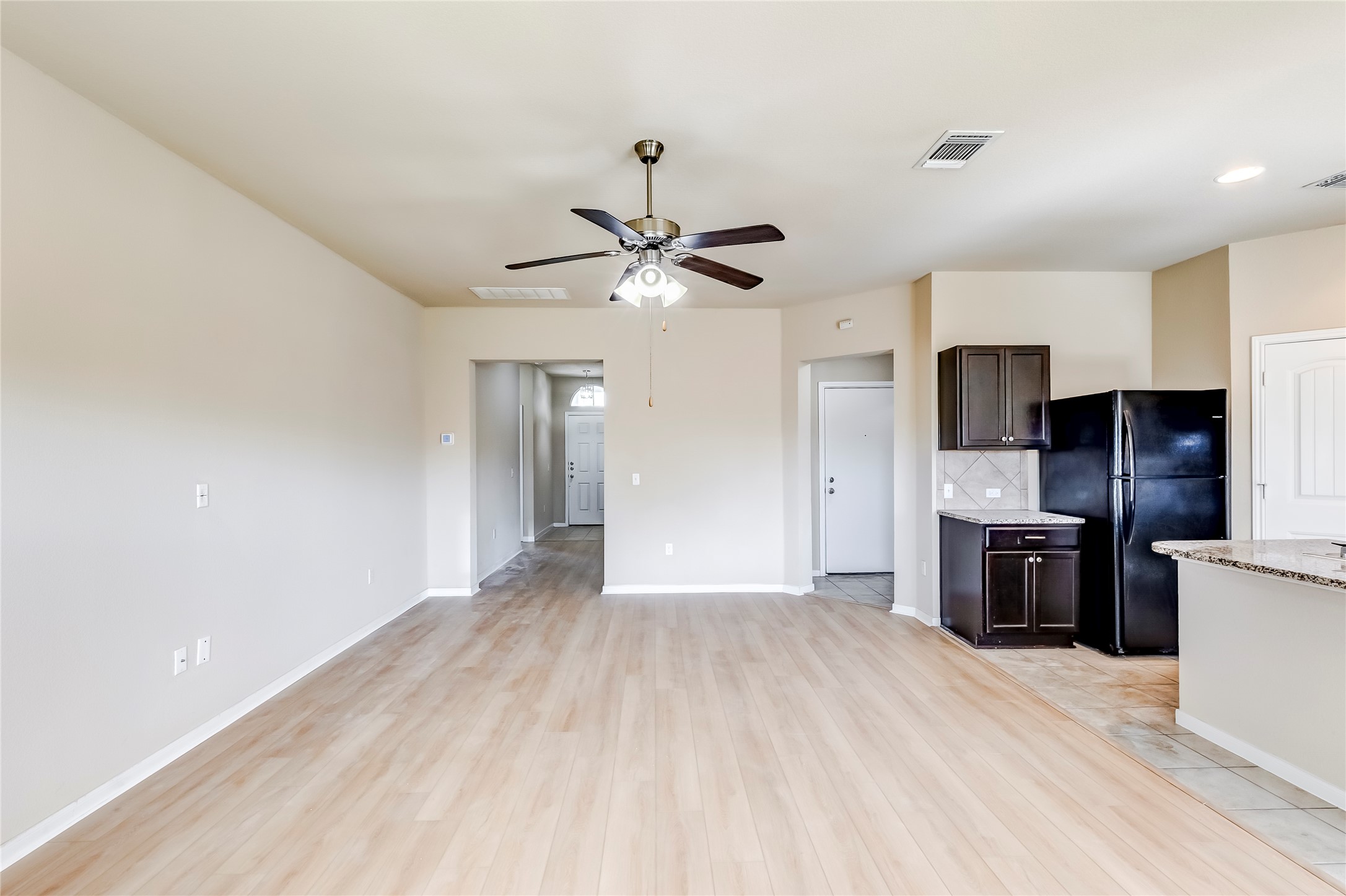 100 Sulphur River Loop Hutto, TX 78634 - Photo 6 of 16 Kitchen with freestanding refrigerator, dark brown cabinets, backsplash, a ceiling fan, and light stone counters