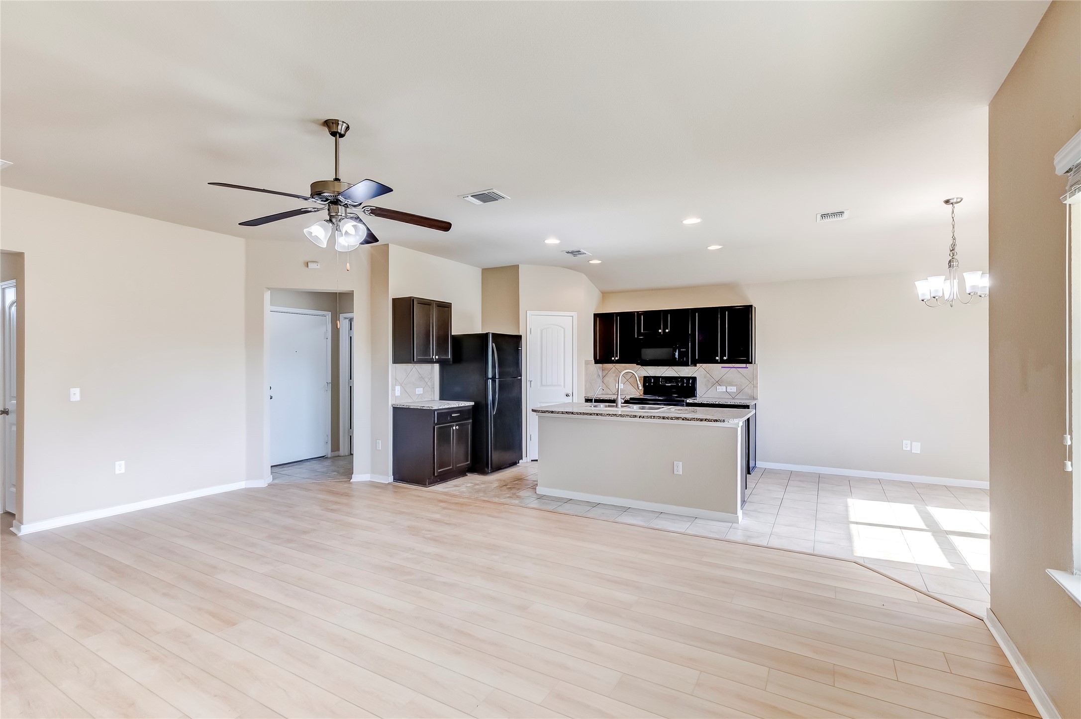 100 Sulphur River Loop Hutto, TX 78634 - Photo 15 of 16 Kitchen featuring open floor plan, decorative backsplash, pendant lighting, a chandelier, and a center island with sink