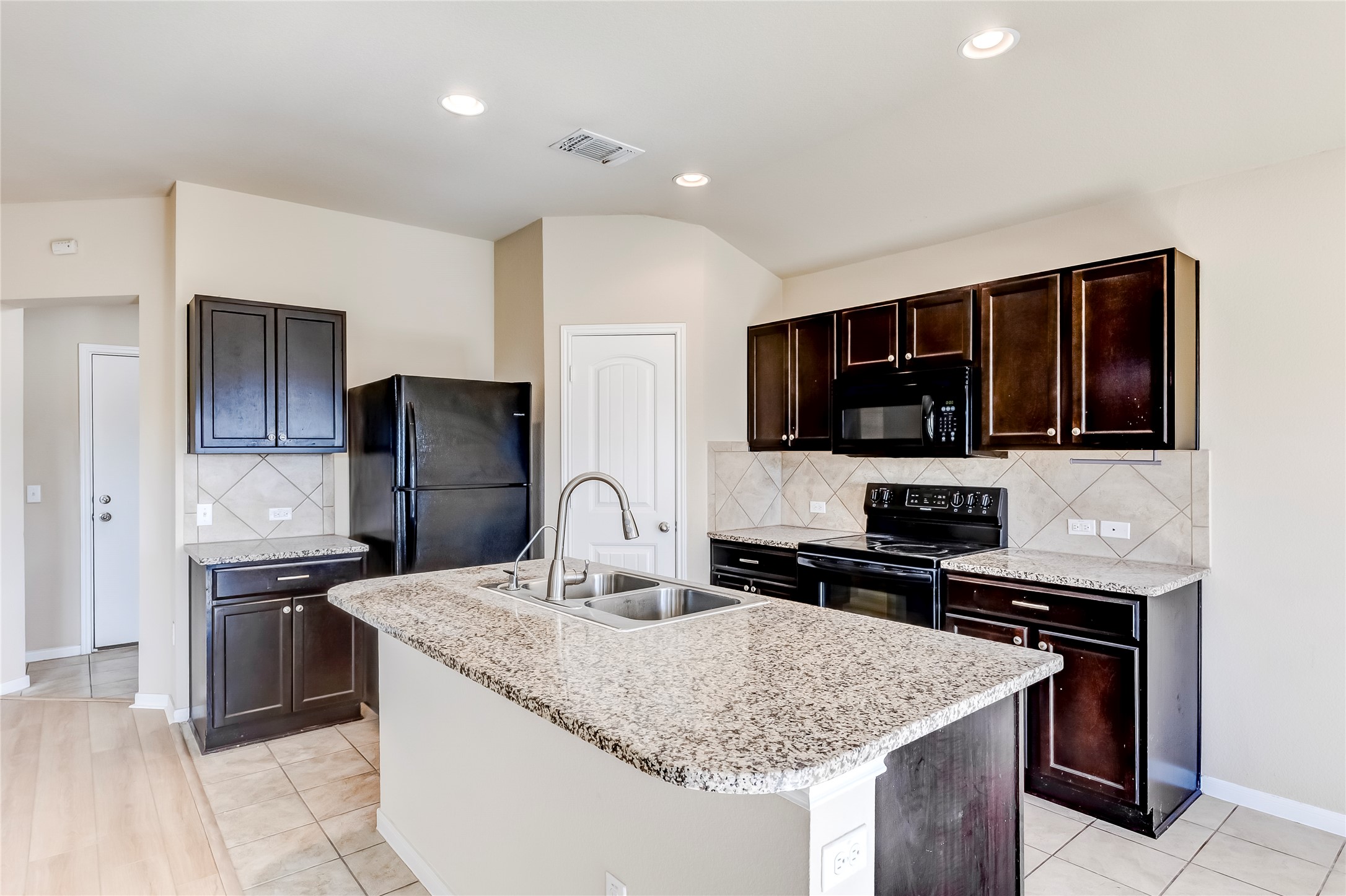 100 Sulphur River Loop Hutto, TX 78634 - Photo 9 of 16 Kitchen featuring backsplash, black appliances, dark brown cabinetry, light stone counters, and recessed lighting