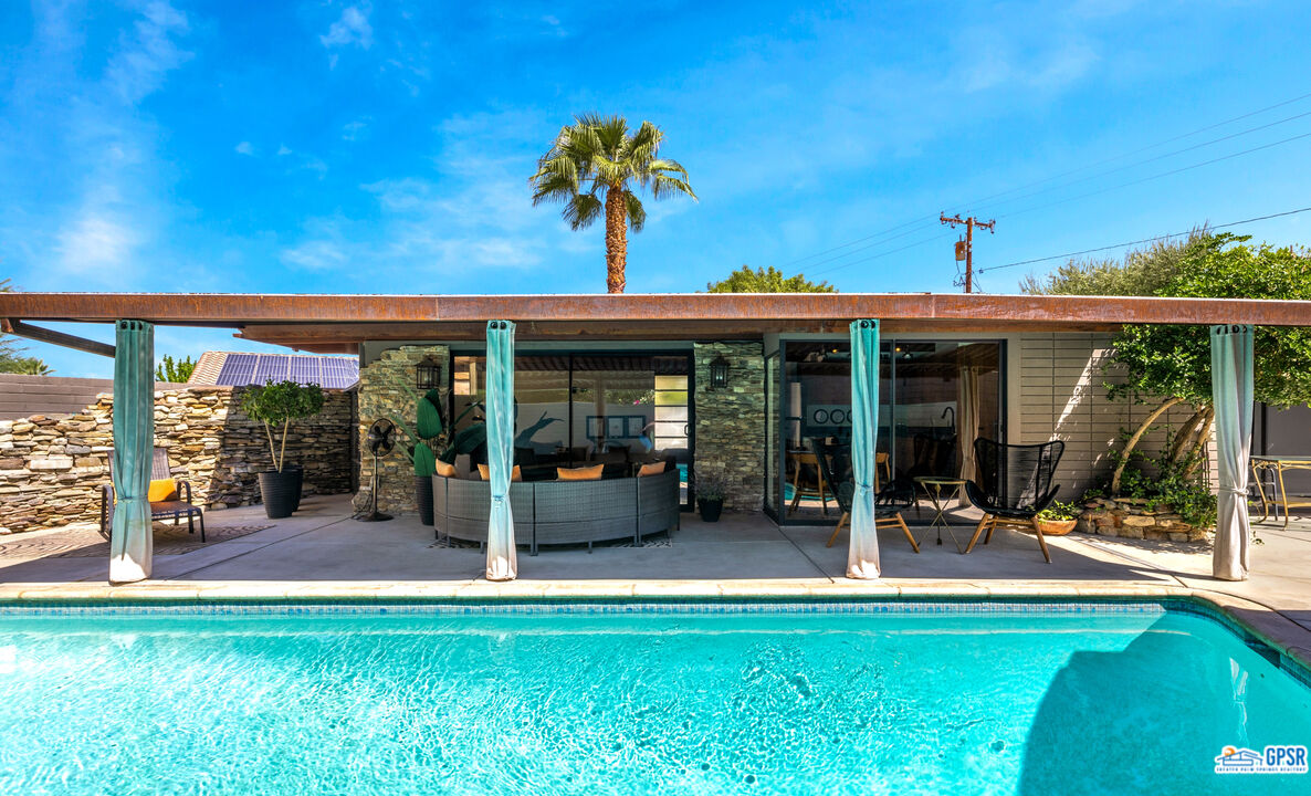 45666 Shadow Mountain Drive Palm Desert, CA 92260 - Photo 40 of 73 a view of a house with floor to ceiling windows and a lawn chairs with plants