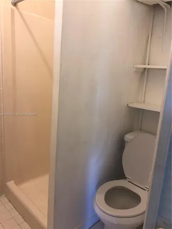 a white toilet sitting next to a shower