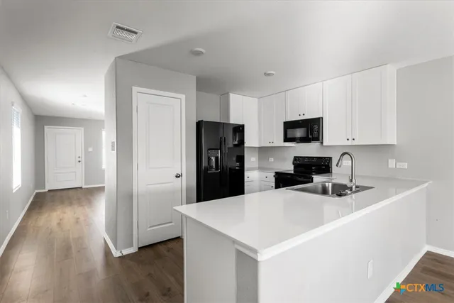 a kitchen with a sink a refrigerator a microwave and cabinets