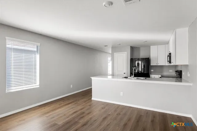 a living room with stainless steel appliances kitchen island wooden floors and white walls