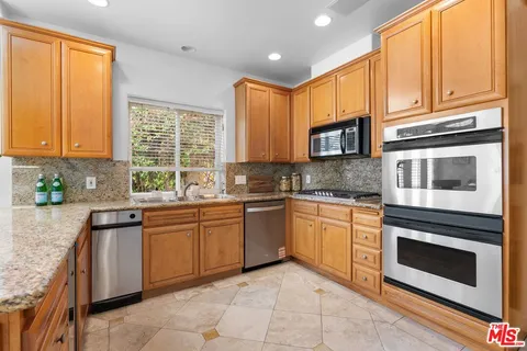 a kitchen with stainless steel appliances granite countertop wooden cabinets and a stove top oven