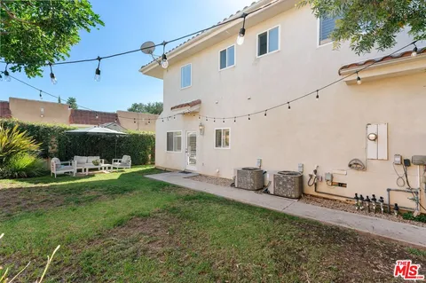 a patio with tables and chairs under an umbrella