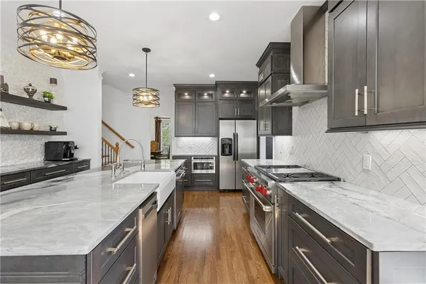 a very nice looking kitchen with granite countertop a stove two sinks and a wooden floor