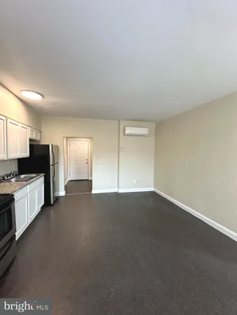 a view of an empty room and a kitchen