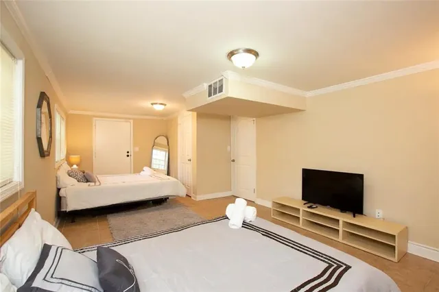 a bedroom with bed and a flat tv screen on dresser