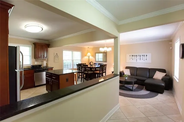 a living room with furniture a large window and stainless steel appliances
