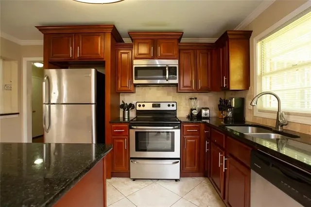a kitchen with granite countertop stainless steel appliances a stove a sink and a microwave