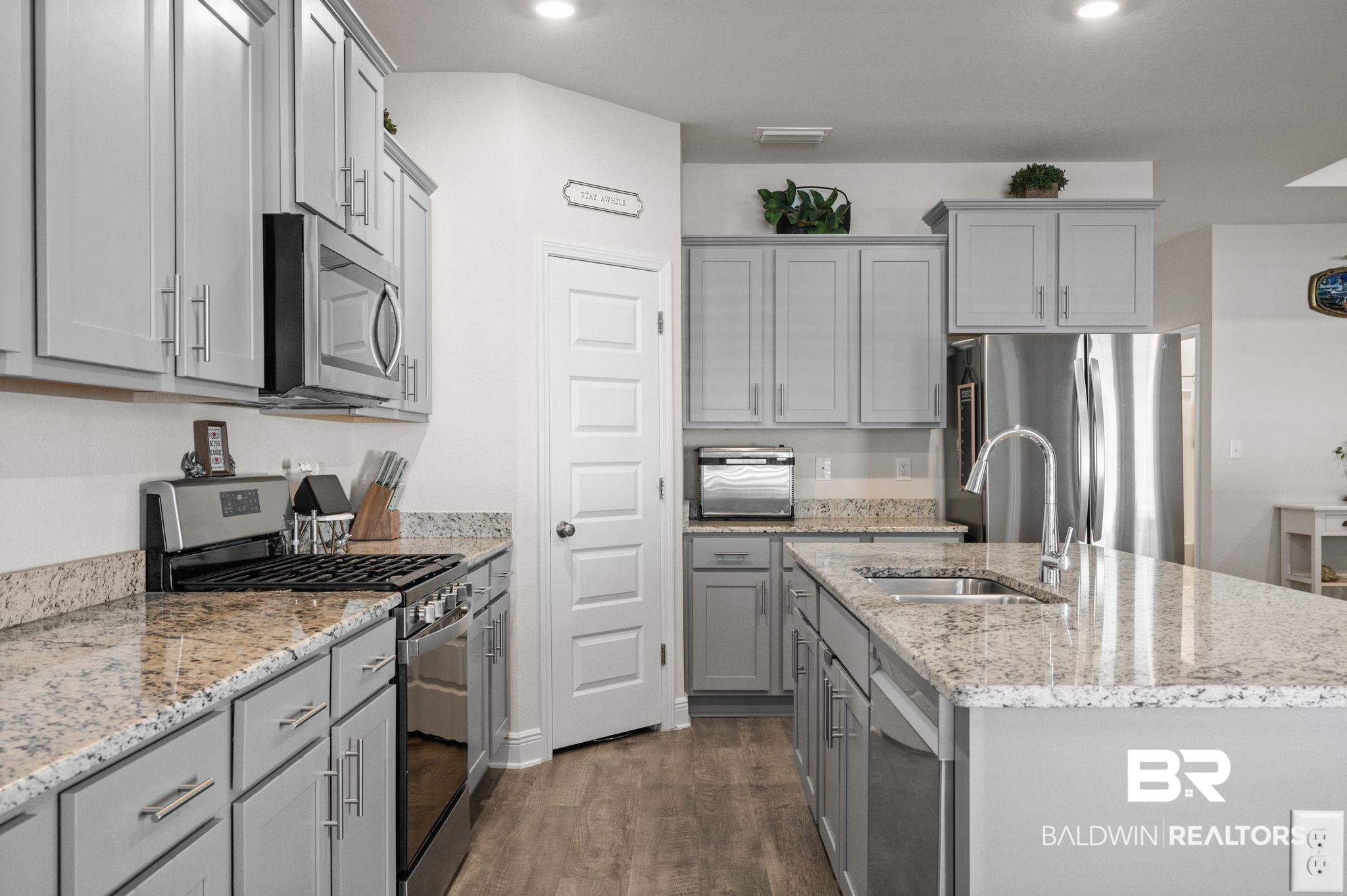24891 Spectacular Bid Loop Daphne, AL 36526 - Photo 20 of 51 Kitchen with dark wood-type flooring, sink, a center island with sink, gray cabinets, and stainless steel appliances