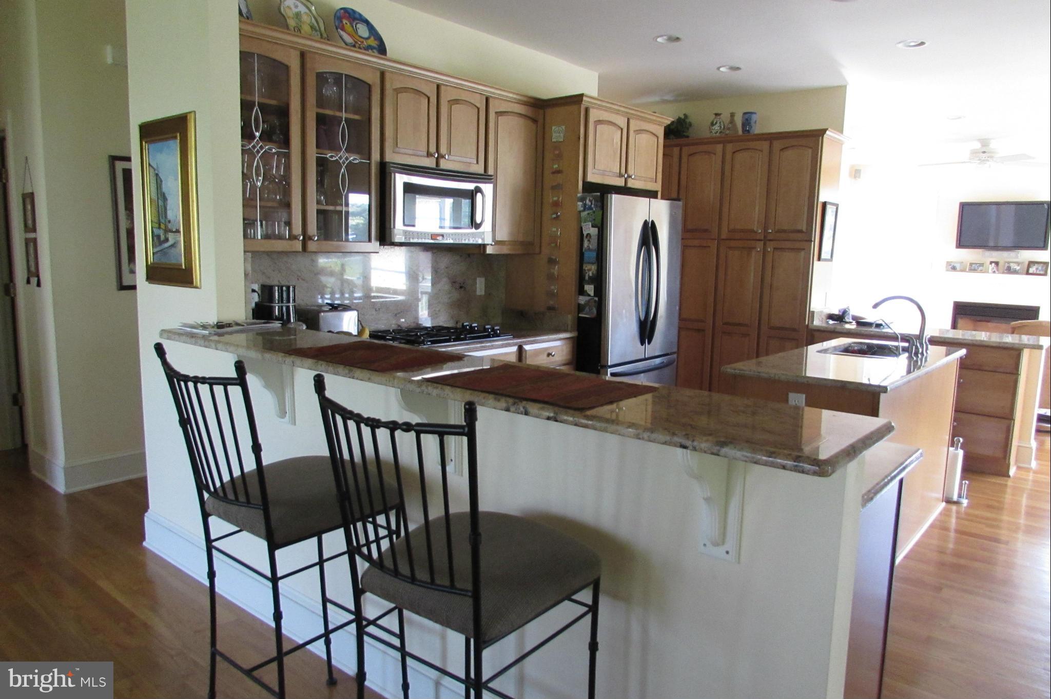 201 Greenwood Creek Road Queenstown, MD 21658 - Photo 7 of 25 a kitchen with stainless steel appliances granite countertop a stove a refrigerator a kitchen island and chairs