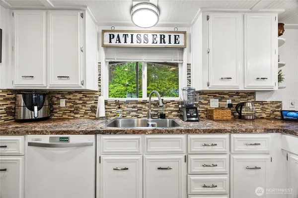 a kitchen with granite countertop white cabinets and window