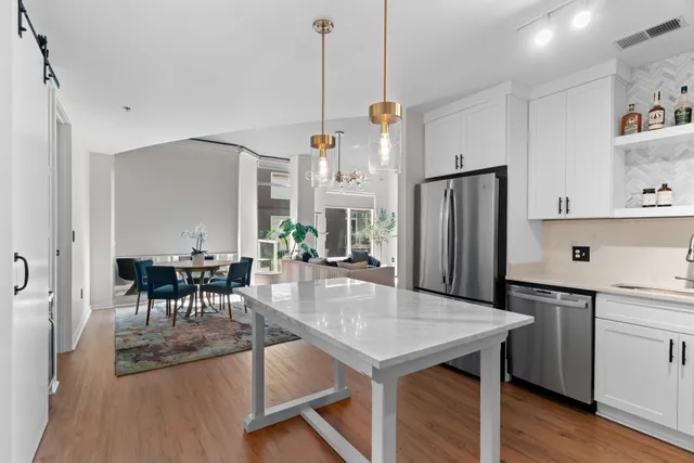 a kitchen with stainless steel appliances granite countertop a table chairs and a refrigerator