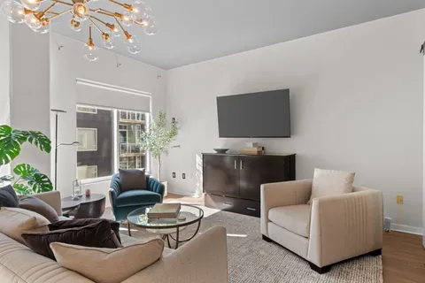 a living room with furniture a flat screen tv and a large window