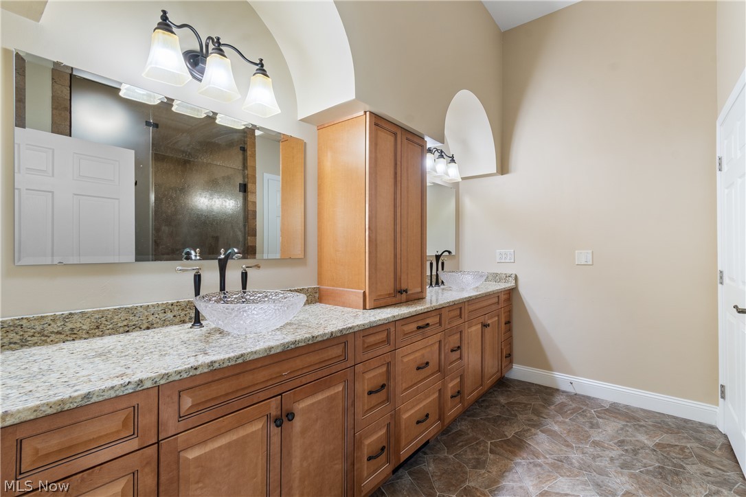 22840 Buck Road Alliance, OH 44601 - Photo 10 of 36 Bathroom with double vanity, dark stone finish flooring, and a shower
