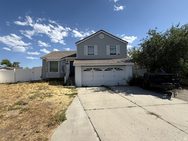 7989 Washington Road Magna, UT 84044 - Photo 2 of 2 Two-story residence featuring light blue siding, a two-car garage, and a concrete driveway